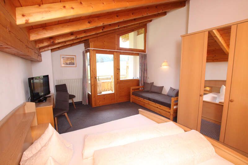 Double bed with couch, desk and view to the balcony in room 4 in Haus Astrid