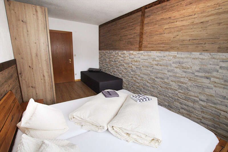 Bedroom with double bed and extra bed in holiday apartment 2 in Haus Astrid in Tyrol